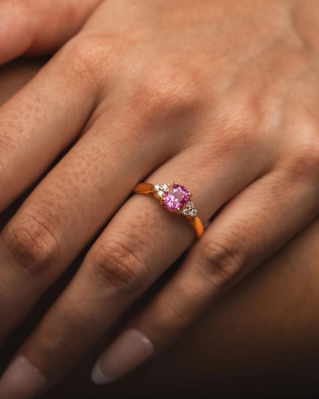 Pink gemstone ring with diamond accents in rose gold worn on a hand