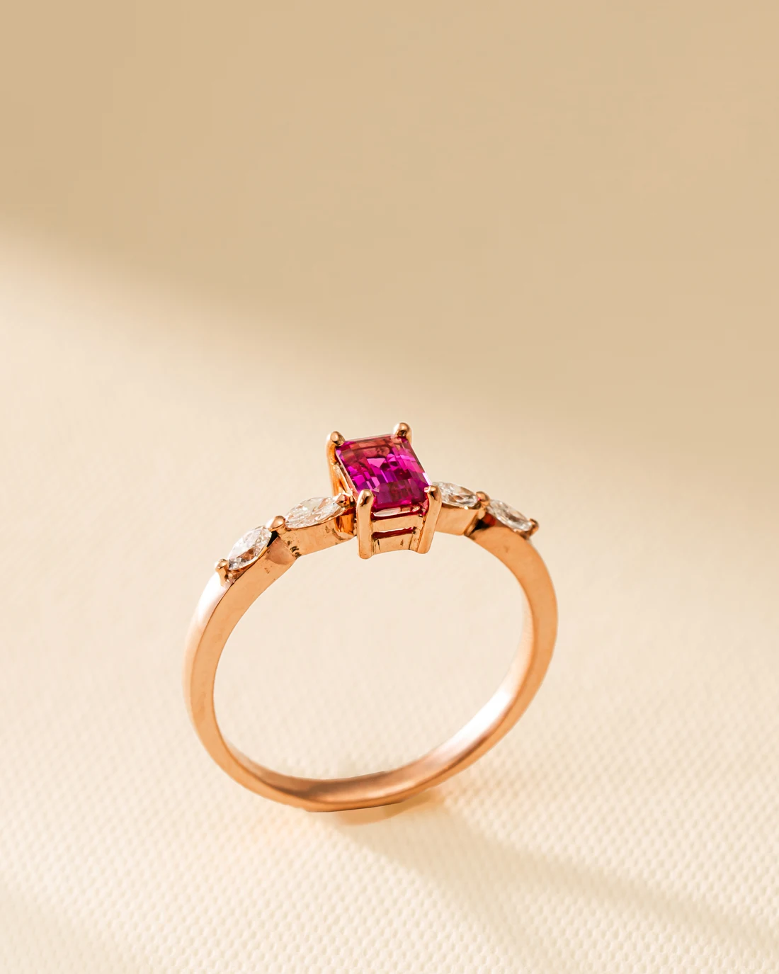 Ruby emerald-cut ring in rose gold photographed in warm studio light